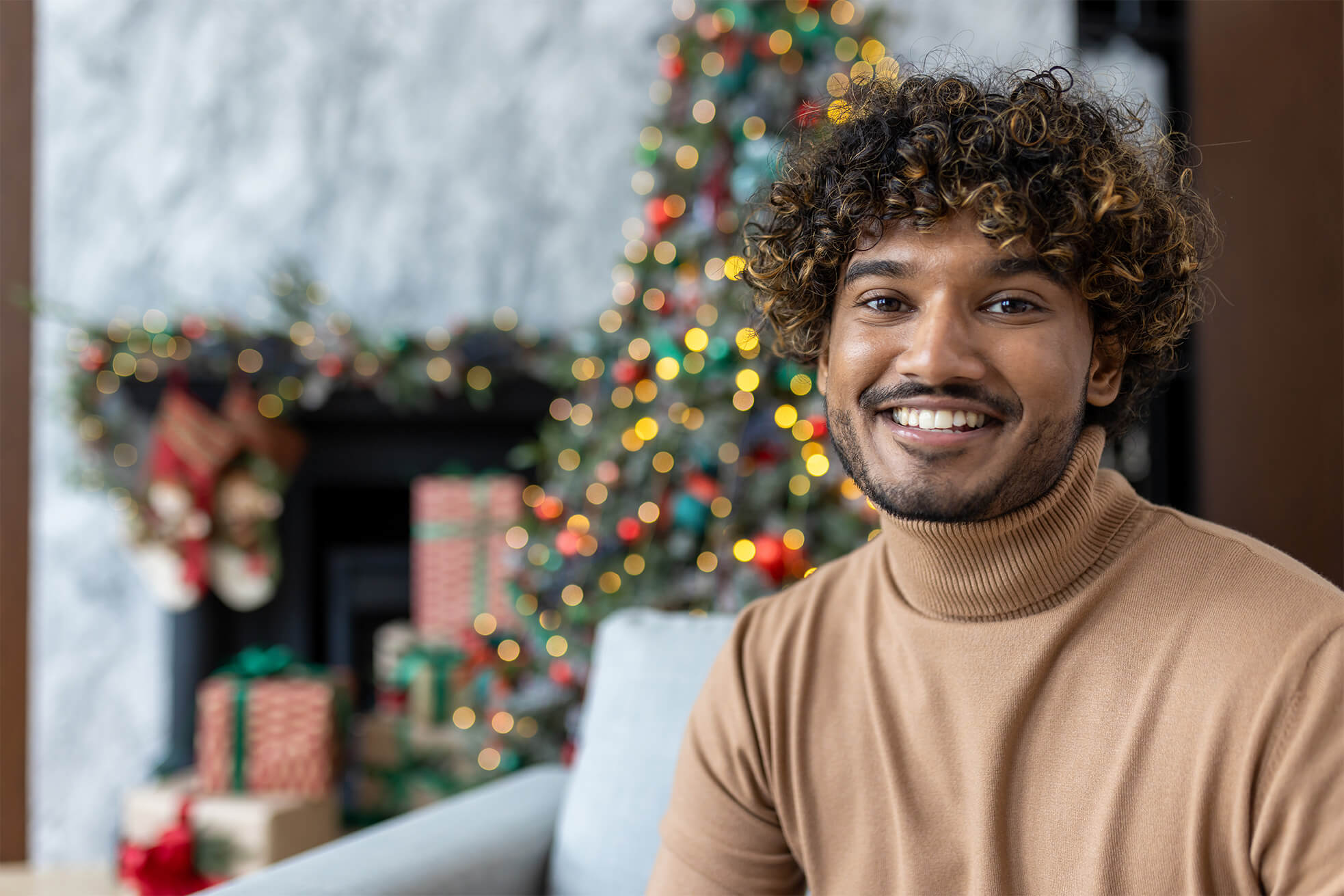 Young person smiling at the camera in front of christmas tree